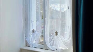 A window with white curtains and a leaf-shaped decoration.