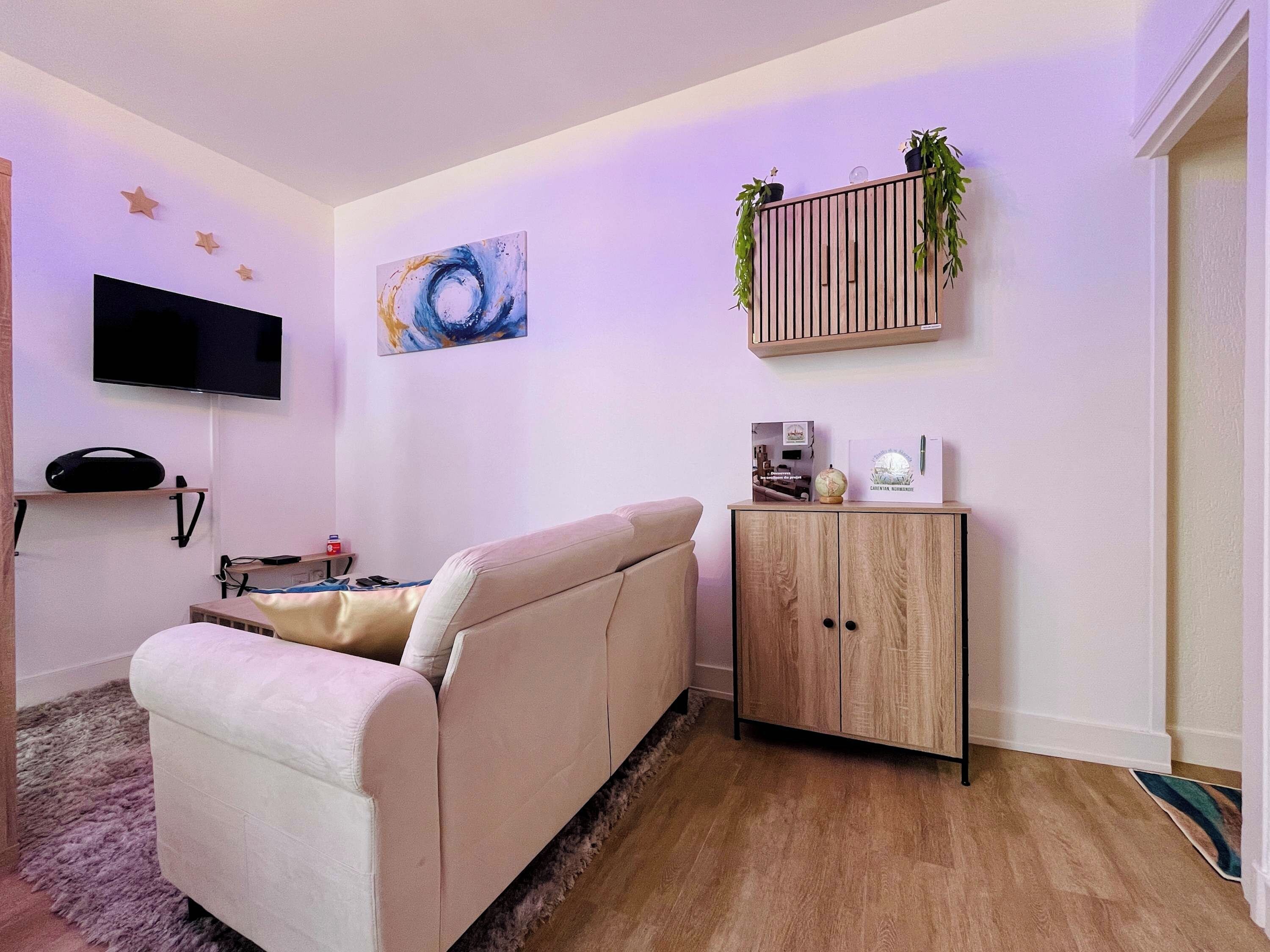 A living room with a sofa, a flat-screen TV, a painting, a cabinet with plants, and a globe.