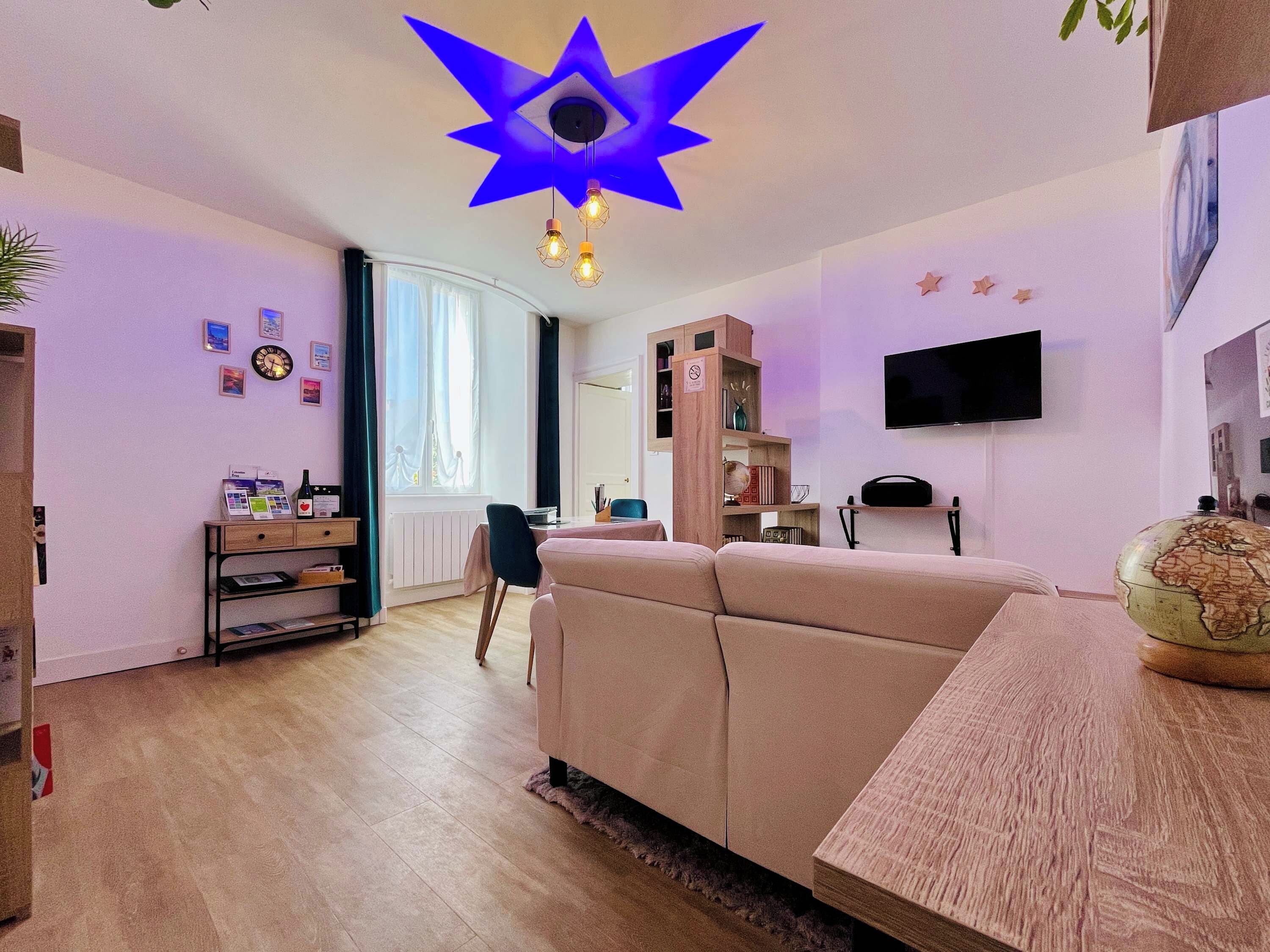 Un salon comprenant un canapé, une table basse, un téléviseur fixé au mur et un globe terrestre posé sur une table d’appoint.