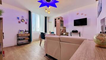 Un salon comprenant un canapé, une table basse, un téléviseur fixé au mur et un globe terrestre posé sur une table d’appoint.