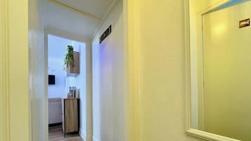 A hallway with a striped rug, a wooden cabinet, and a plant on the wall.