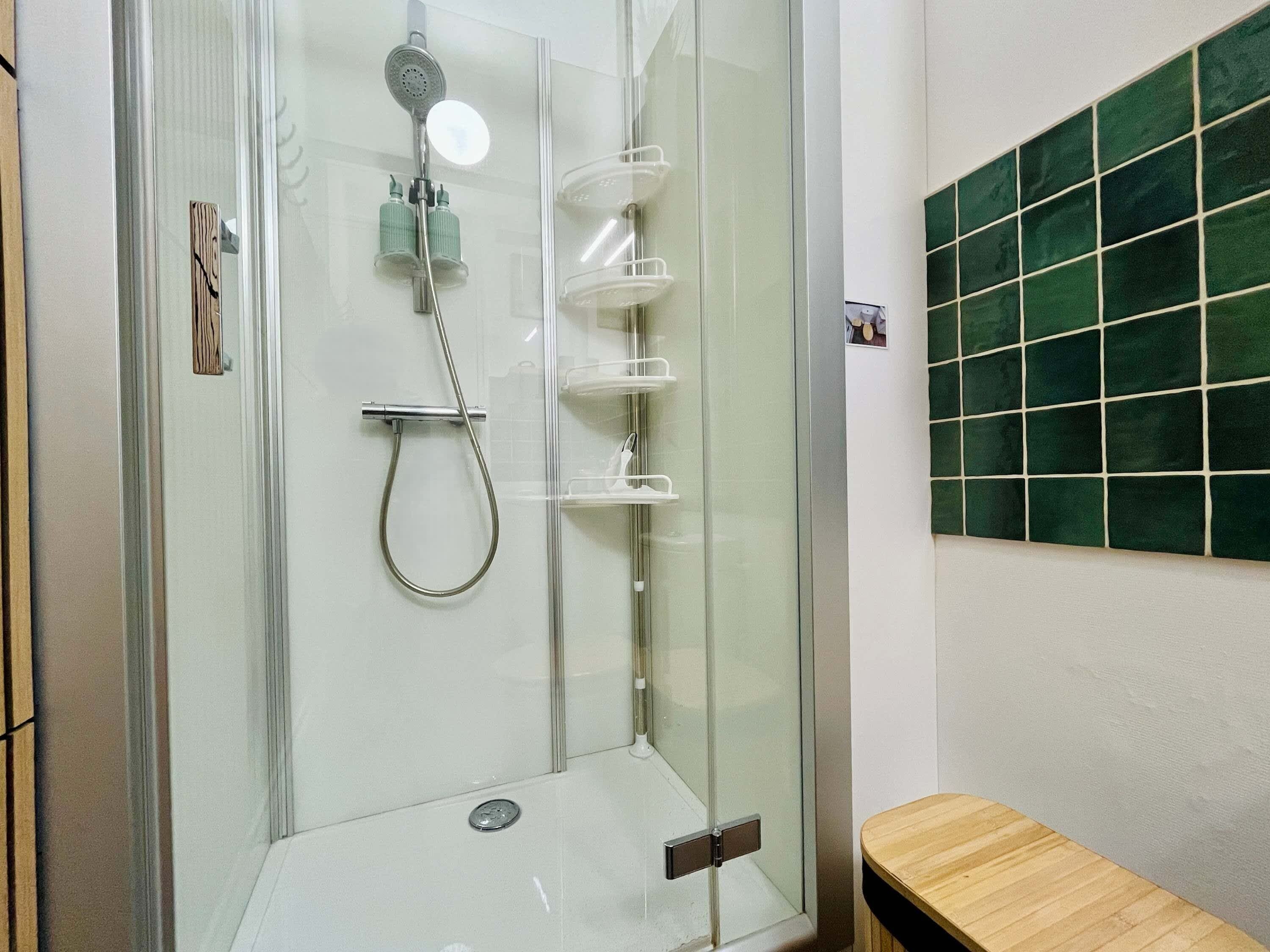 Een douchecel met glazen wanden, een handdouche en een kraan op de muur.