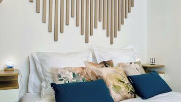Une chambre à coucher moderne avec un lit, des coussins décoratifs, un luminaire fixé au mur et une table de chevet.