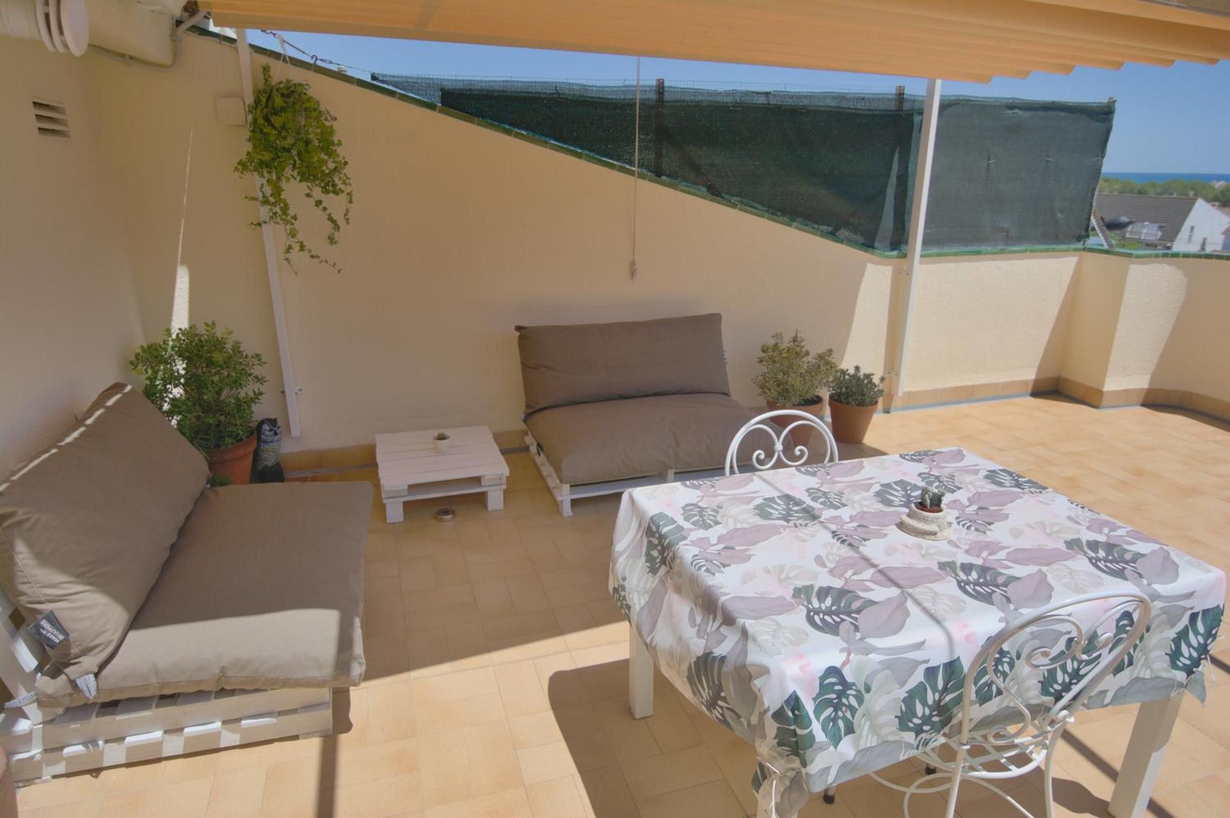 An outdoor patio with a sofa, a small table, and a dining table with chairs.