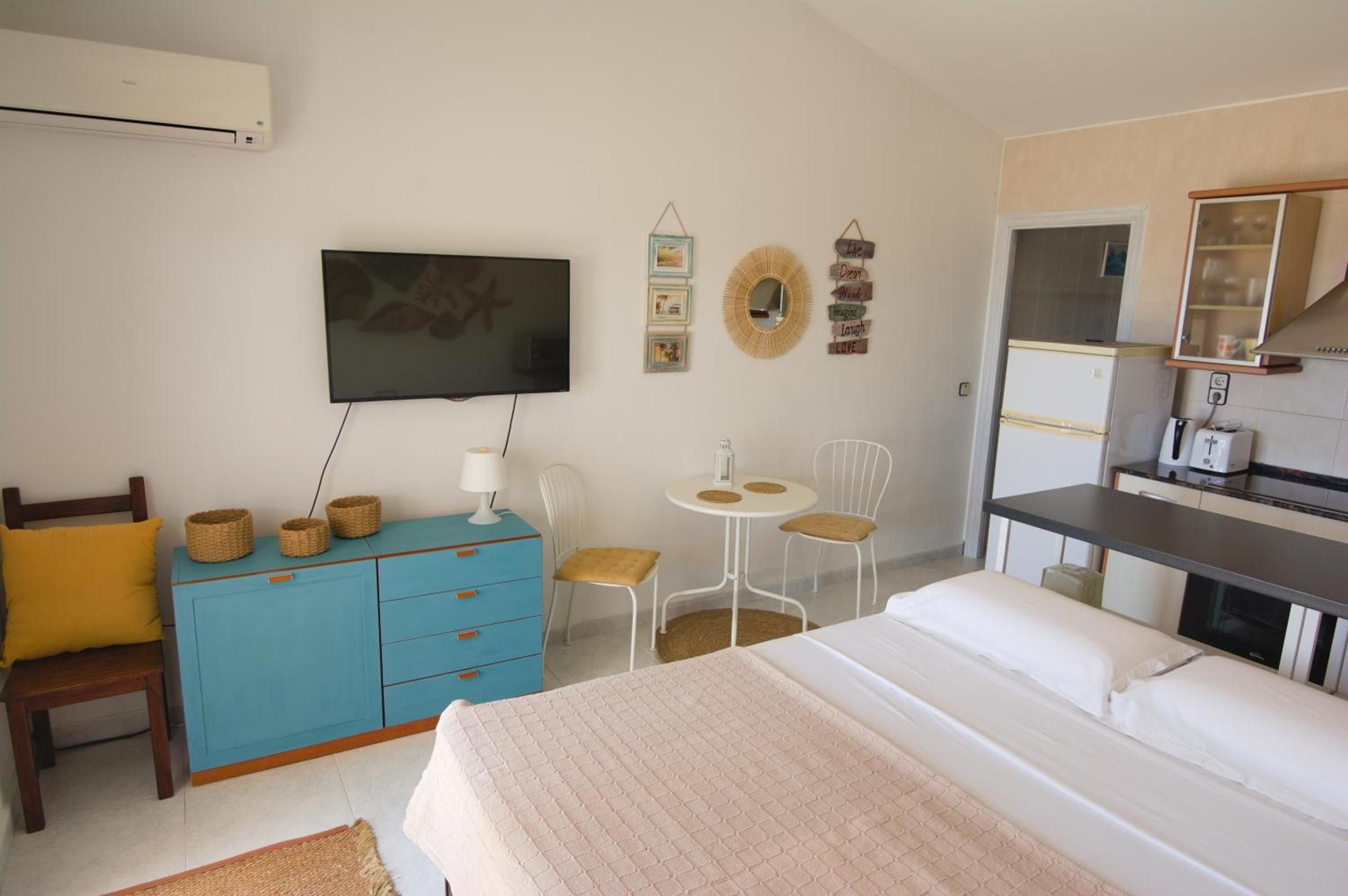 Une chambre comprenant un lit, une télévision, un bureau et un coin cuisine.