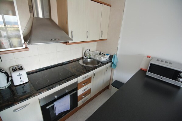 A kitchen with a stove, oven, sink, and cabinets. - Apartment 'Sunny Home' with Sea View and Large Terrace (Cunit)