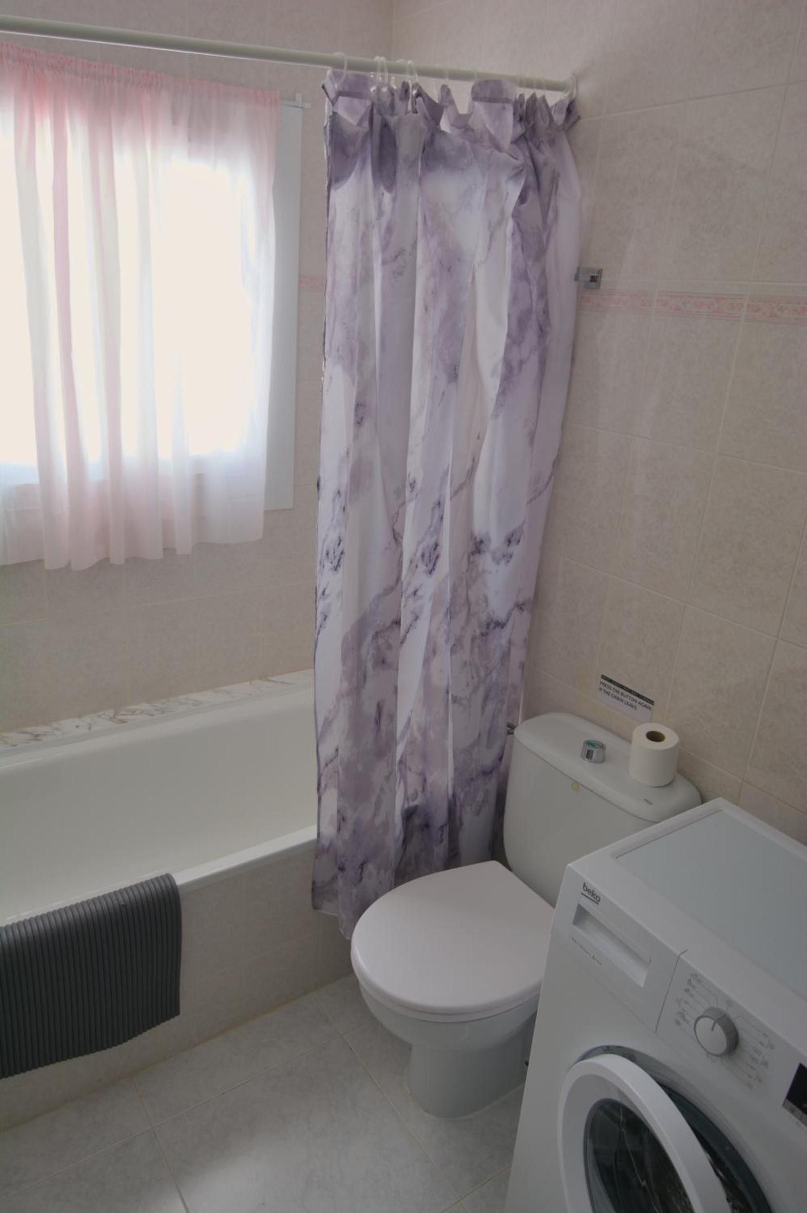 A bathroom with a bathtub, toilet, and washing machine.