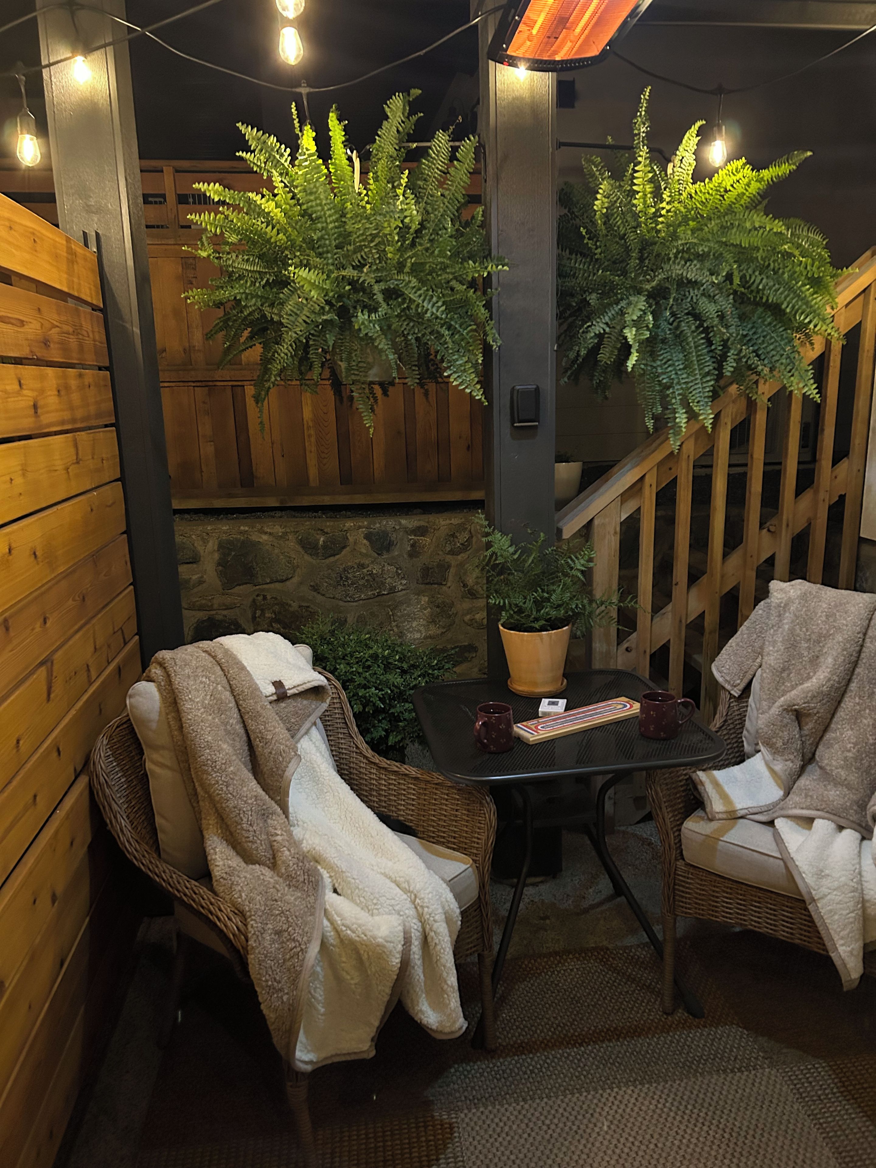 A cozy seating area with two wicker chairs, a small table, and a potted plant.