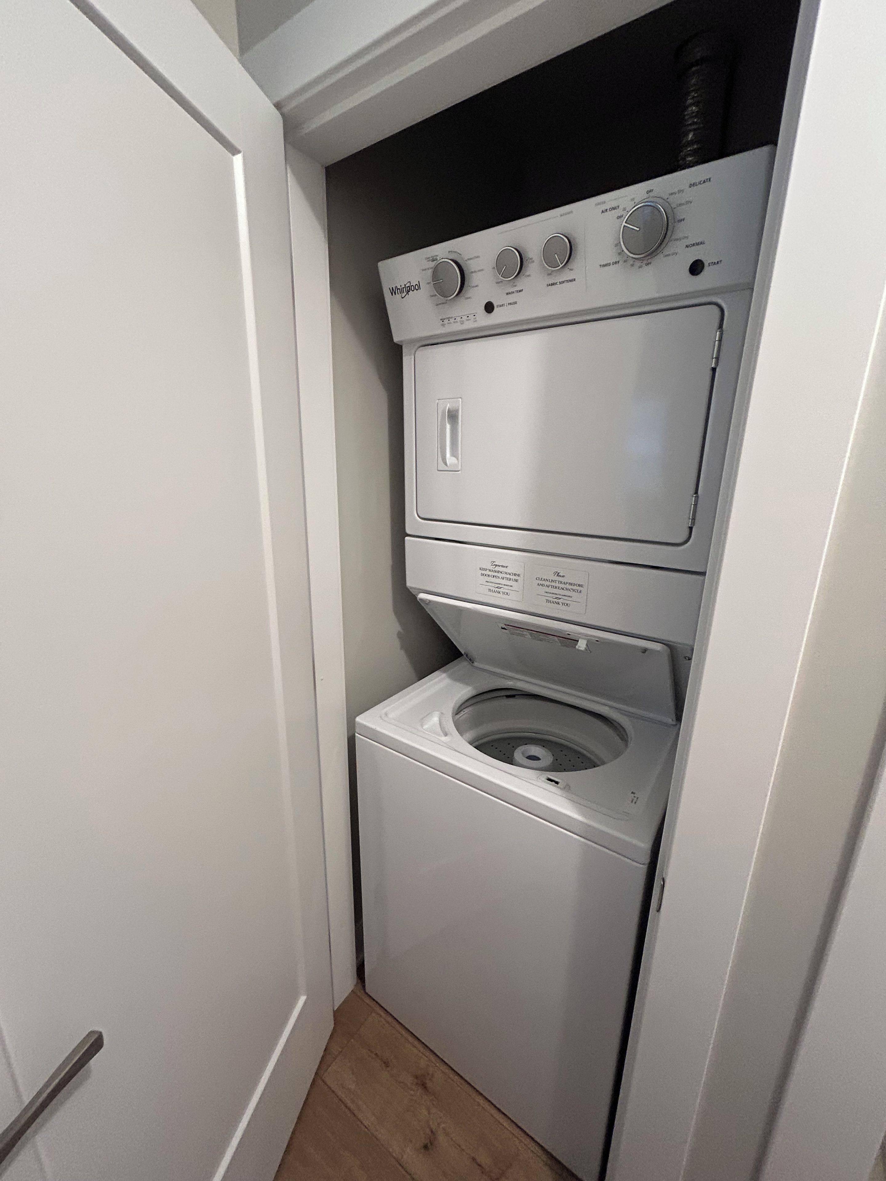 Une petite buanderie blanche, dotée de deux portes, et comprenant un lave-linge et un sèche-linge à chargement frontal.