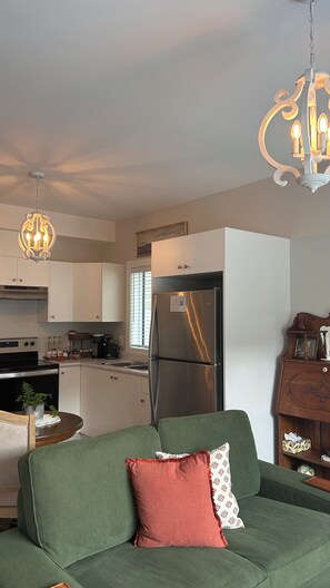 A modern kitchen with white cabinets, a stainless steel refrigerator, and a hanging light fixture. - Fall Escape for 2 • King Bed • Fireplace • 
Heated Private Patio • Free Parking (Victoria)