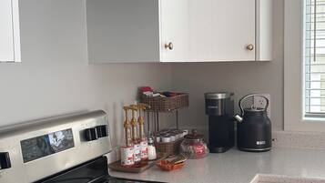 A modern kitchen with stainless steel appliances, white cabinetry, and a window with blinds.