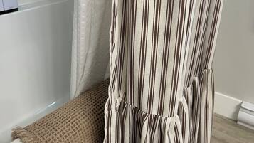 A bathroom with a bathtub, a shower curtain, and a towel.