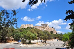 A view of ancient ruins on a hill with trees and a clear sky. - Cute apartment in Acropolis (Athens)