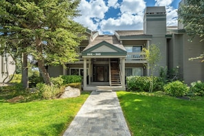 A two-story house with a covered front porch, a brick pathway leading to the entrance, and a well-maintained lawn. - Close to Downtown | Fireplace (Mammoth Lakes)