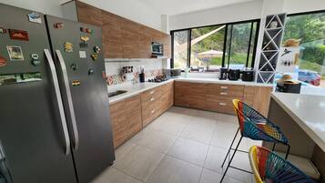 A modern kitchen with a refrigerator, wooden cabinets, and a large window.