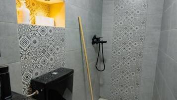 A bathroom with patterned tiles, a toilet, a bidet, and a mop.