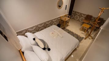 Habitación de hotel con cama, una silla, una mesita y un espejo en la pared.