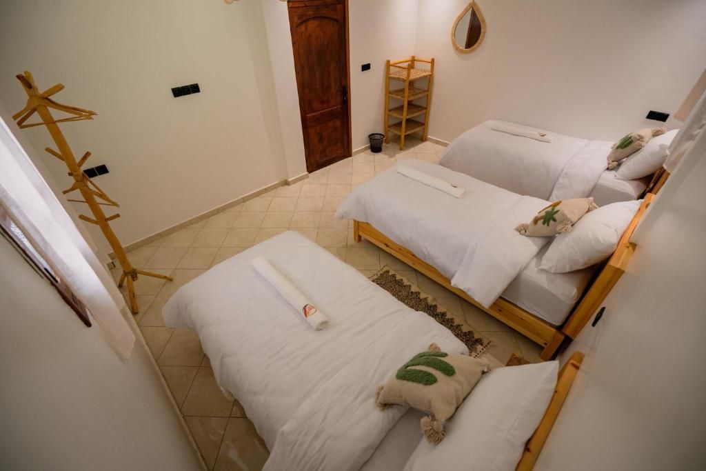 A room with two beds, a wooden ladder, a wooden coat rack, and a door.