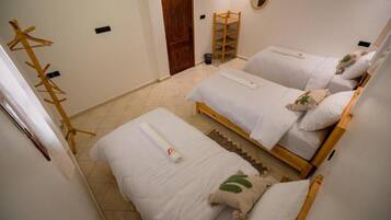 A room with two beds, a wooden ladder, a wooden coat rack, and a door.