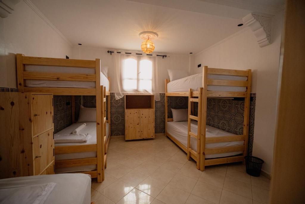 Quarto com beliches, guarda-roupa de madeira e parede estampada.