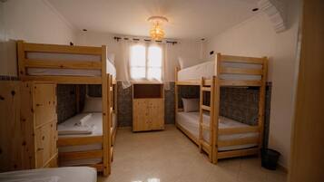 Quarto com beliches, guarda-roupa de madeira e parede estampada.