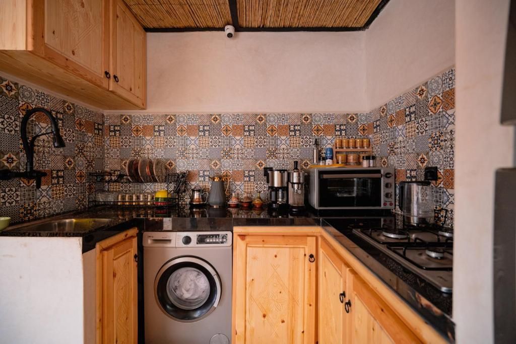 Una cocina con lavadora, armarios de madera y un salpicadero estampado.