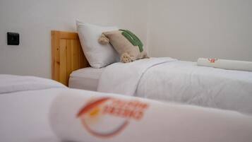 A hotel room with a wooden headboard, white bedding, and a single bed.