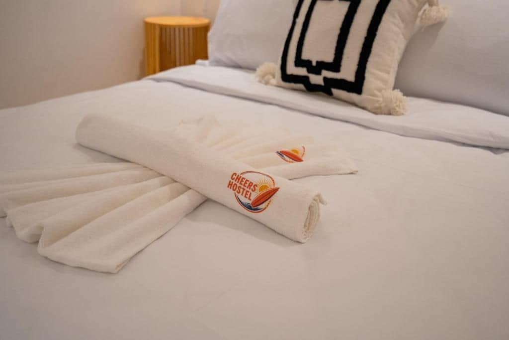A neatly made bed with a white duvet and a towel with a logo.