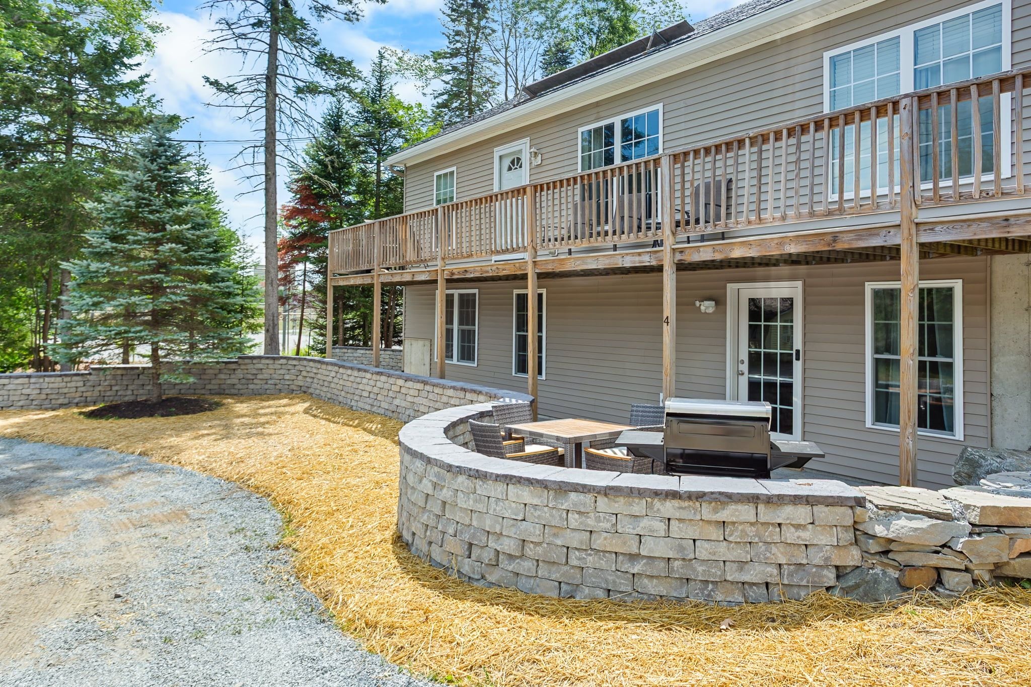 A two-story house with a stone patio and outdoor seating area.