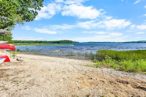 Ett område vid en sjö med en grusgång som leder till en brygga med röda kanoter.