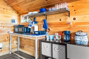 A compact kitchen with essential appliances and a small dining area. - The Cabins on Webb Pond - NEW! Waterfront (Eastbrook)