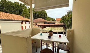 Ein Balkon mit Tisch, Stühlen und einem Blumentopf.