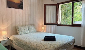 A bedroom with a bed, two bedside lamps, a window with curtains, and a painting on the wall. - House near the beach with terrace and parking (Arcachon)