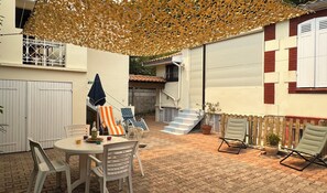 An outdoor patio area with a table, chairs, a striped umbrella, and a decorative canopy. - House near the beach with terrace and parking (Arcachon)