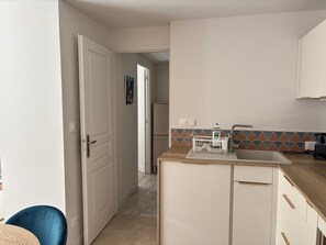 A compact kitchen with a sink, a countertop, and a door leading to another room. - Charming renovated 1-bedroom with garden & parking (Aix-en-Provence)