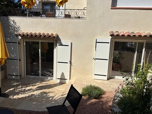 A patio area with a chair, a small plant, and a potted plant. - Charming renovated 1-bedroom with garden & parking (Aix-en-Provence)
