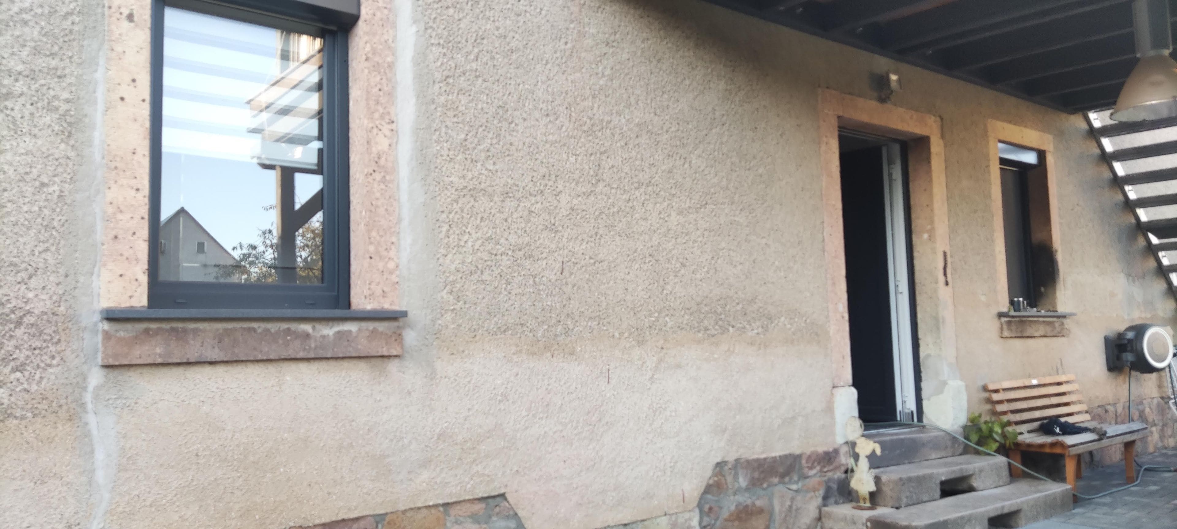 A building exterior with a window, a door, and a bench.