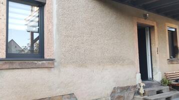 A building exterior with a window, a door, and a bench.