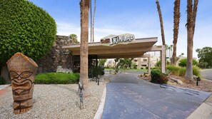 A hotel entrance with a stone facade, palm trees, and a sign reading 'Trinidad Club'. - Club Trinidad Resort by CoolVacay (Palm Springs)
