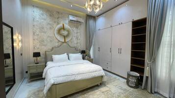 A bedroom with a large bed, a wardrobe, a mirror, and a chandelier.