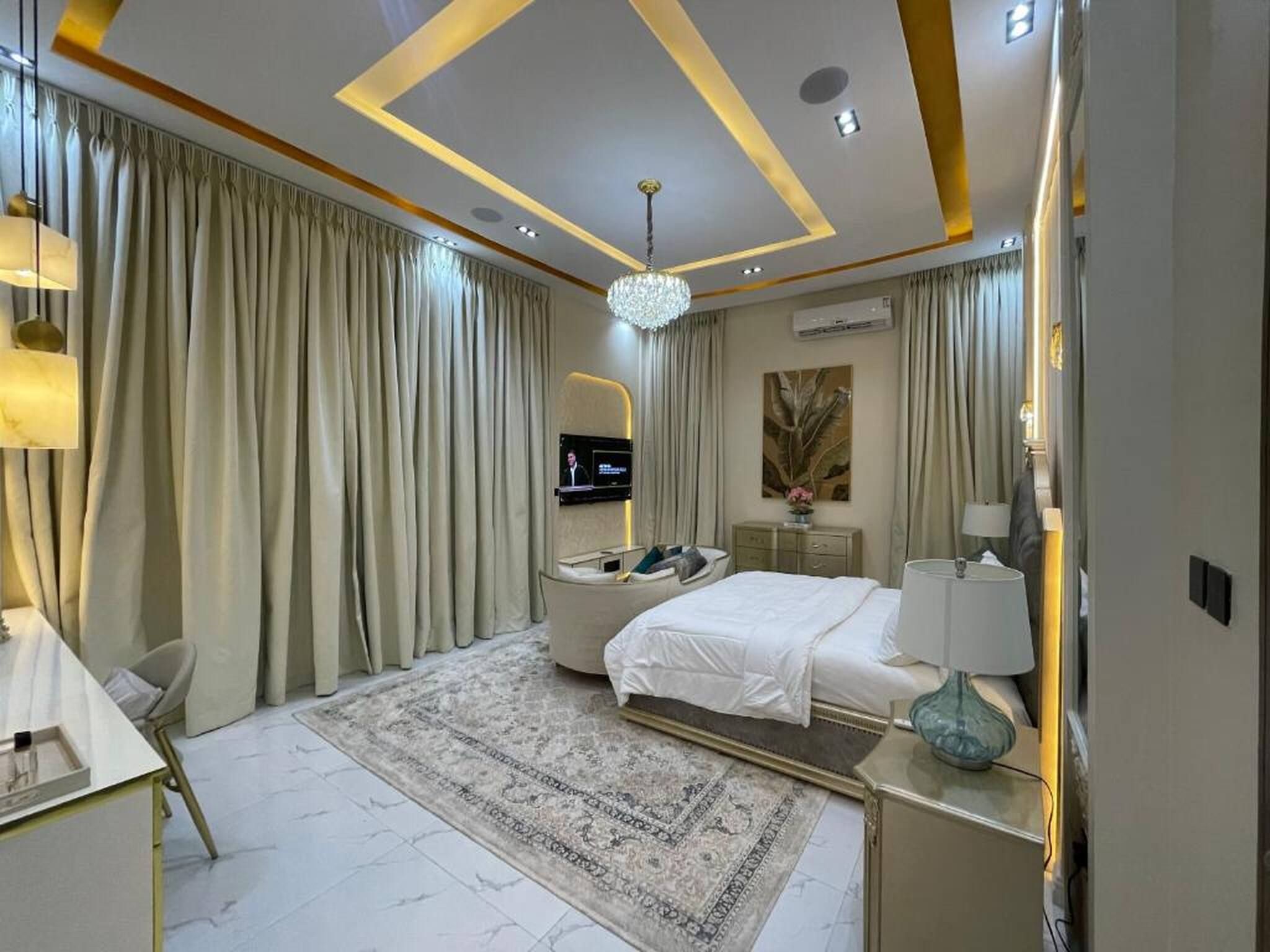 Una habitación de hotel moderna con una cama grande, un escritorio, un televisor y un candelabro decorativo.
