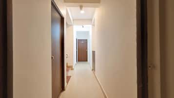A narrow hallway with a wooden door on the left and a white wall on the right.