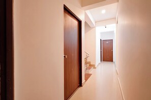 Un pasillo con puerta de madera, una escalera y una puerta con el número 202.