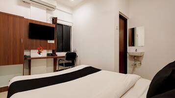 Une chambre d’hôtel comprenant un lit, un bureau avec une chaise, une télévision, un miroir et un lavabo.