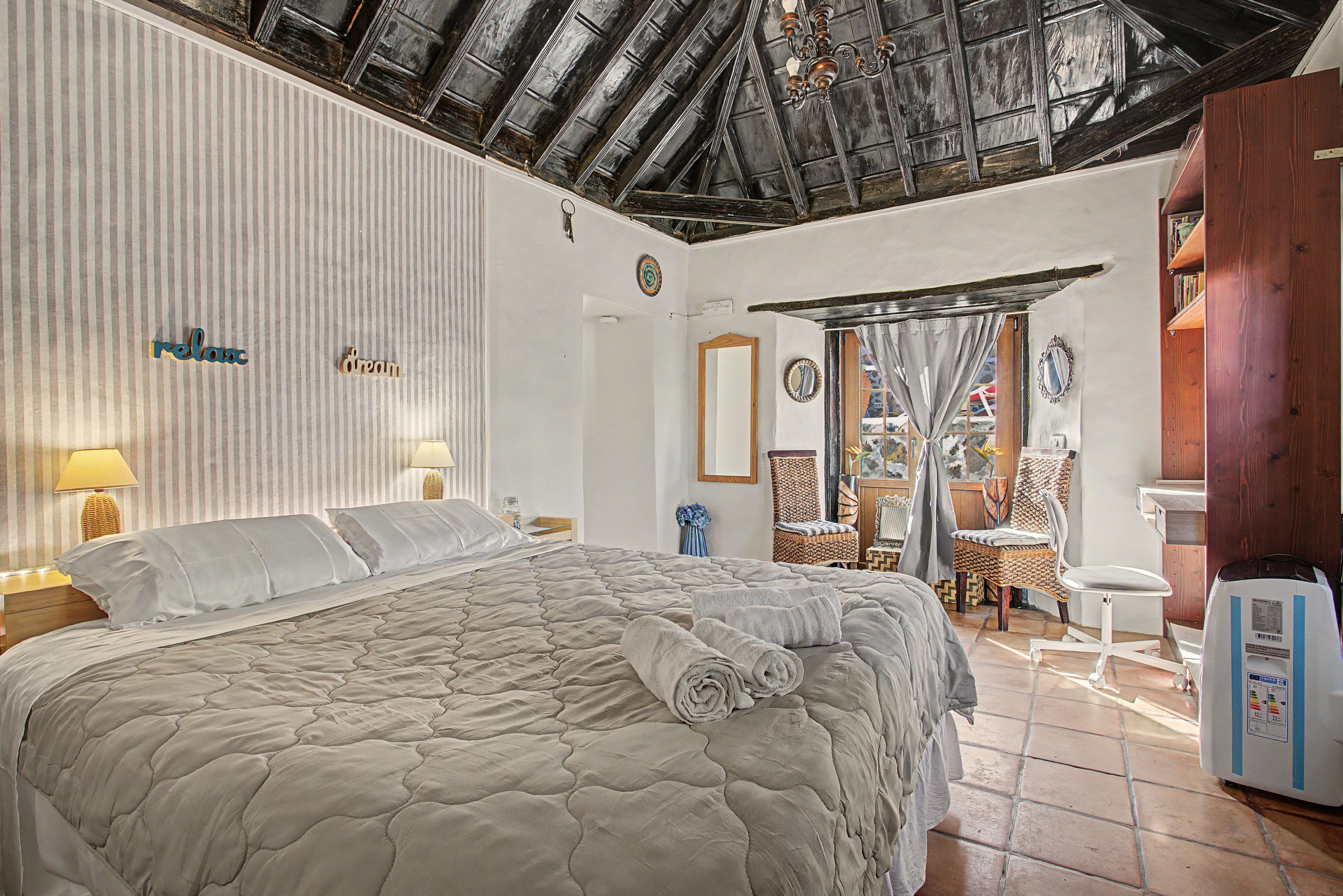 Une chambre d’hôtel avec un grand lit, une table de chevet, une lampe, un miroir et une vue sur l’extérieur.
