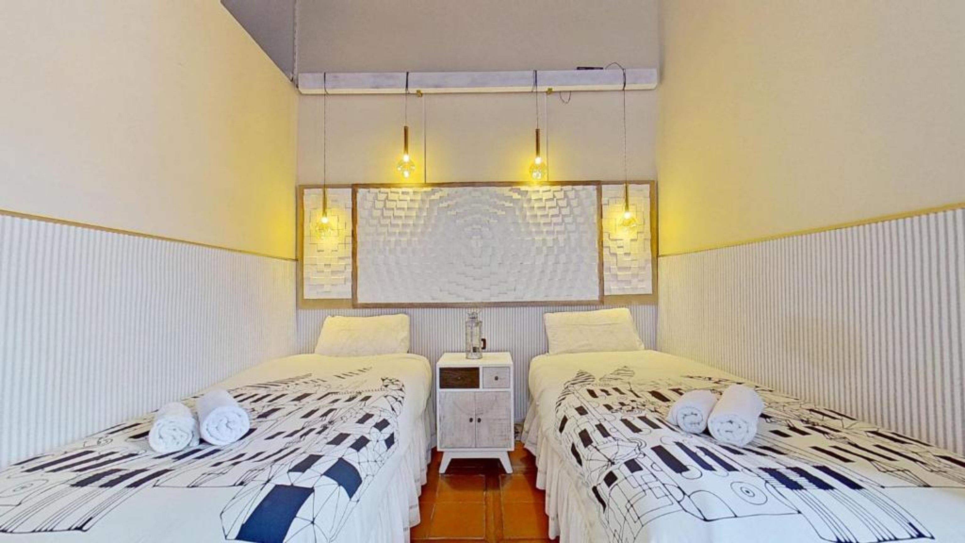 Une chambre d’hôtel avec deux lits, une table de chevet et un luminaire fixé au mur.