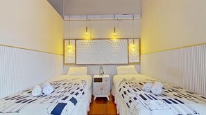 Une chambre d’hôtel avec deux lits, une table de chevet et un luminaire fixé au mur.