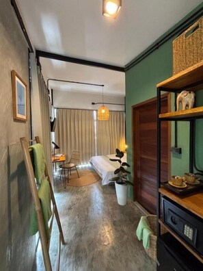 Ein Zimmer mit einem Bett, einem Schreibtisch, einem Stuhl, einer Zimmerpflanze und einem Regal mit Dekoration.
