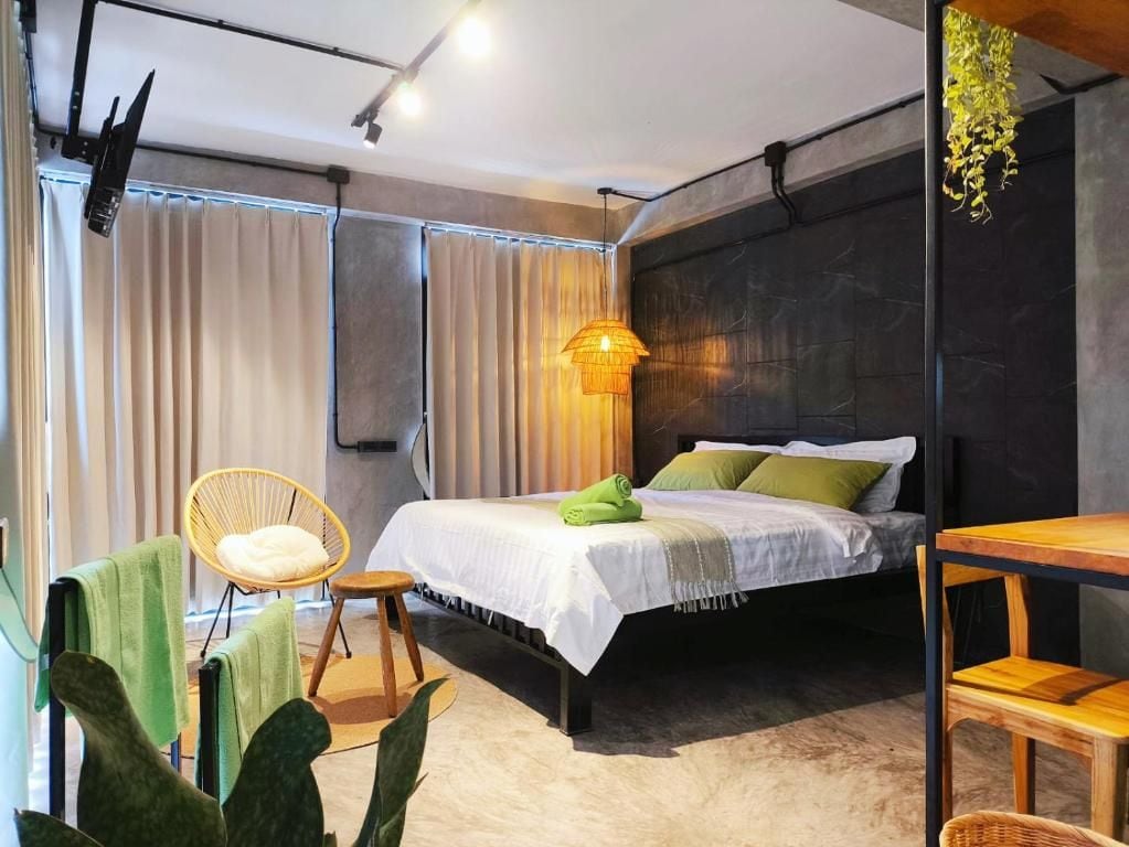 Een moderne slaapkamer met een bed, een stoel, een tafeltje en een hangplant.