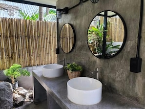 Ein Badezimmer mit zwei Waschbecken, einem Spiegel und einem kleinen Topfpflanzen.
